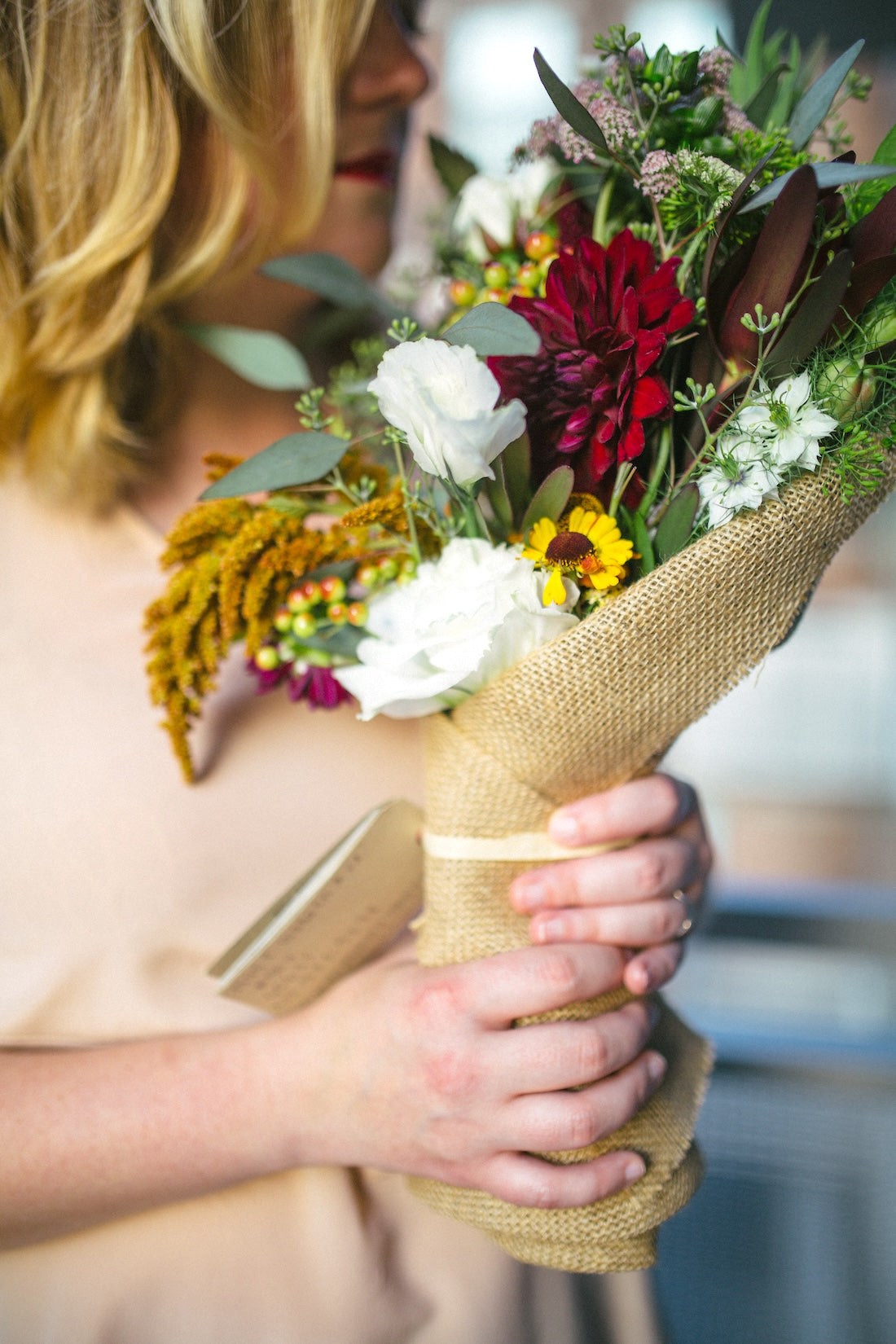 Customer holding seasonal subscription bouquet wrapped in burlap from Flowers for Dreams