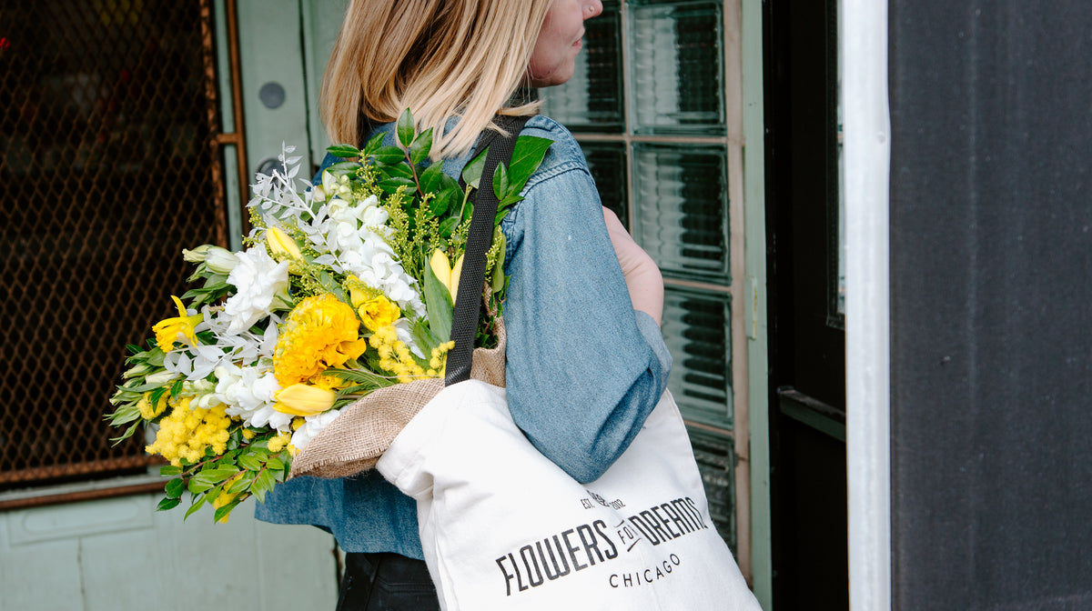 Floral subscription customer holding a fresh bouquet in a Flowers for Dreams tote bag