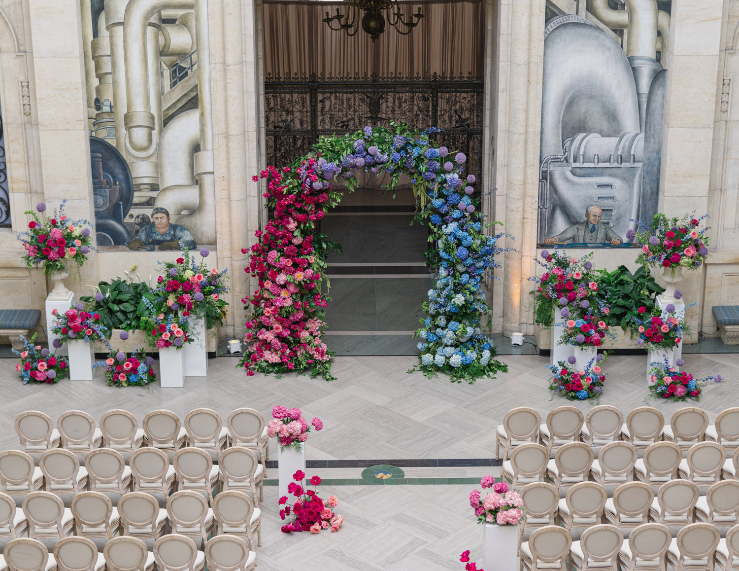Decorative floral archway with flowers on either side of a door, surrounded by chairs.